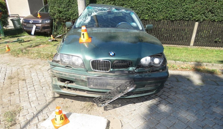 Řidič dostal smyk. Naboural zaparkované auto, plot domu a sloup vysokého napětí