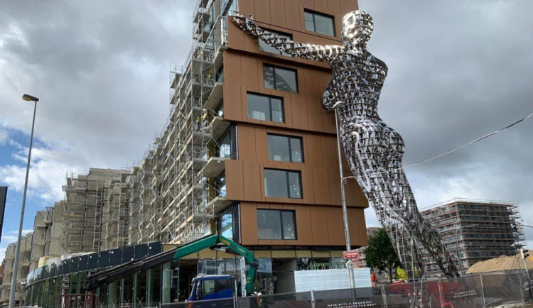 Obří ocelová socha ženy, která podpírá bytový dům, bude otáčet hlavou