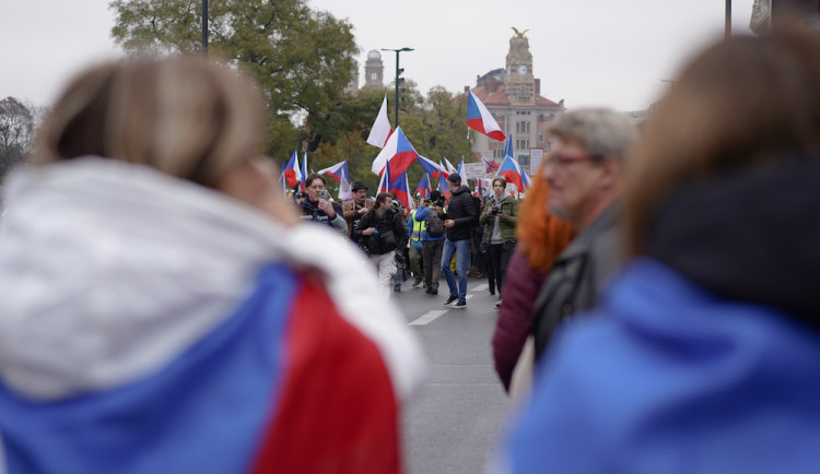 Lidé nesou transparenty a vlajky