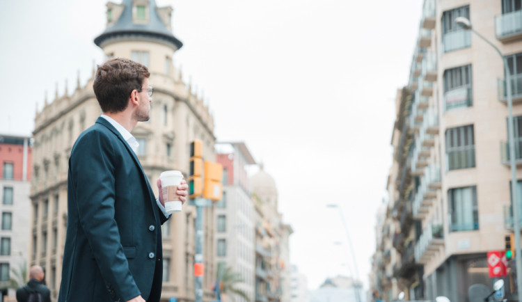 young-businessman-holding-coffee-cup-hand-looking-buildings-city