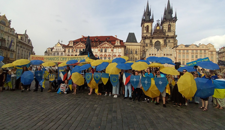 Lidé kolem stánku, který na Staromáku napadli turisté, vytvořili symbolickou hradbu z deštníků
