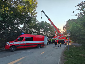 Hasiči auto vytáhnou jeřábem.