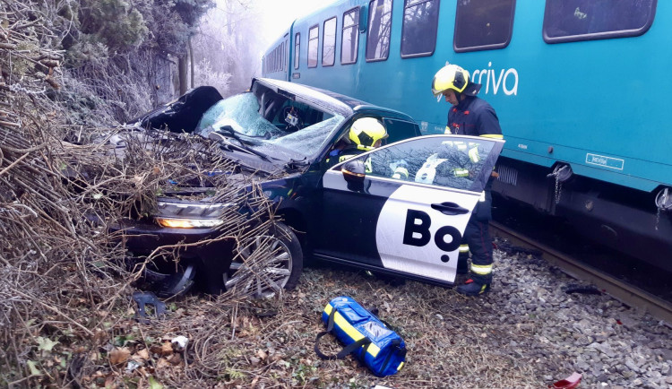 Vlak na přejezdu v Praze smetl auto, řidiče museli hasiči vystříhat