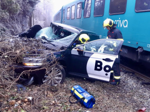 Vlak na přejezdu v Praze smetl auto, řidiče museli hasiči vystříhat