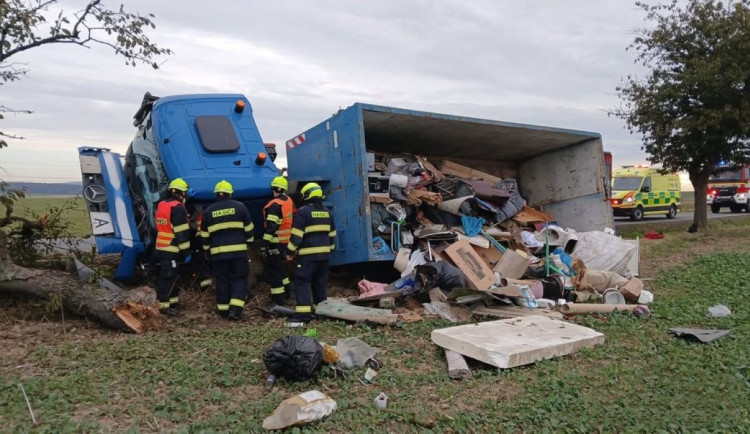Náklaďák s kontejnerem na odpad skončil na boku v příkopu. Řidič se zranil