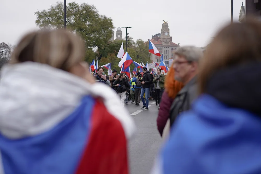 Lidé nesou transparenty a vlajky