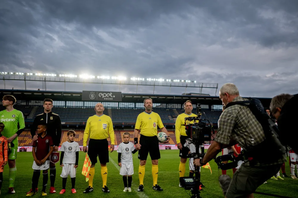 Režisér Kolečko točí film na letenském stadionu, hledá stovky sparťanských komparsistů. Dostanou jídlo a dárek