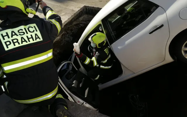 FOTO: Řidička v Praze 10 vjela do výkopu na silnici. Vyprostit ji museli hasiči