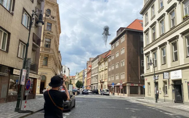 Nad ulicí v centru Prahy se vznáší nová socha. Lidé jsou nadšení i zděšení