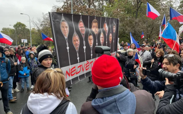 Lidé nesou transparenty a vlajky