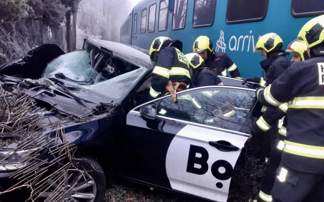 Vlak na přejezdu v Praze smetl auto, řidiče museli hasiči vystříhat