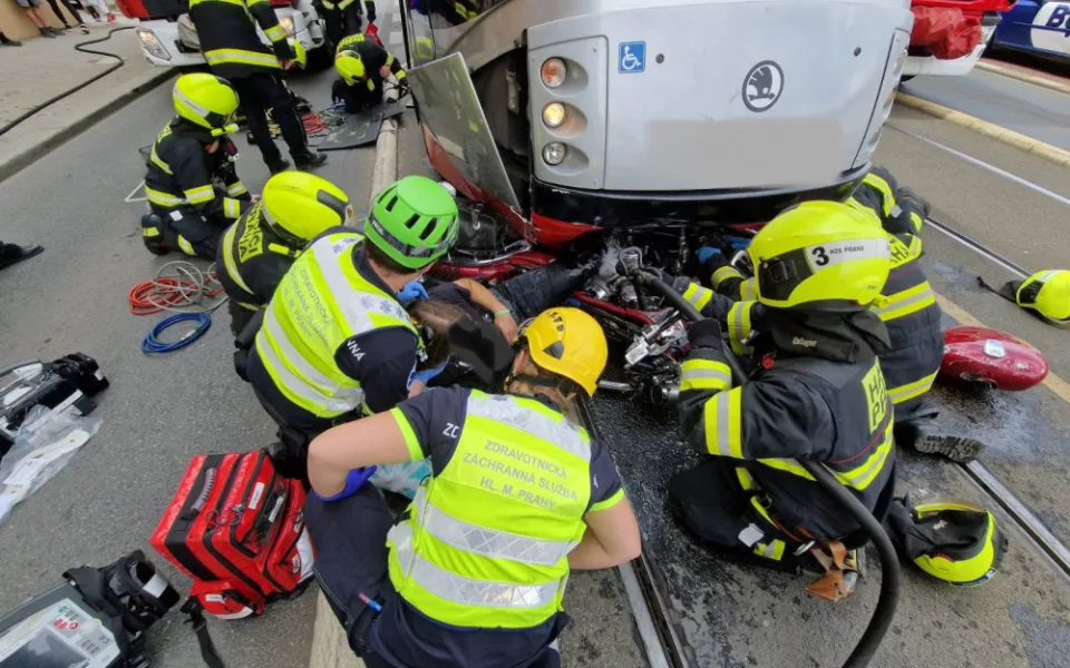 Motorkář skončil zaklíněný pod tramvají. Při vědomí ho vyprošťovali hasiči