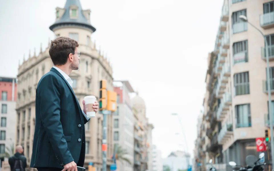 young-businessman-holding-coffee-cup-hand-looking-buildings-city